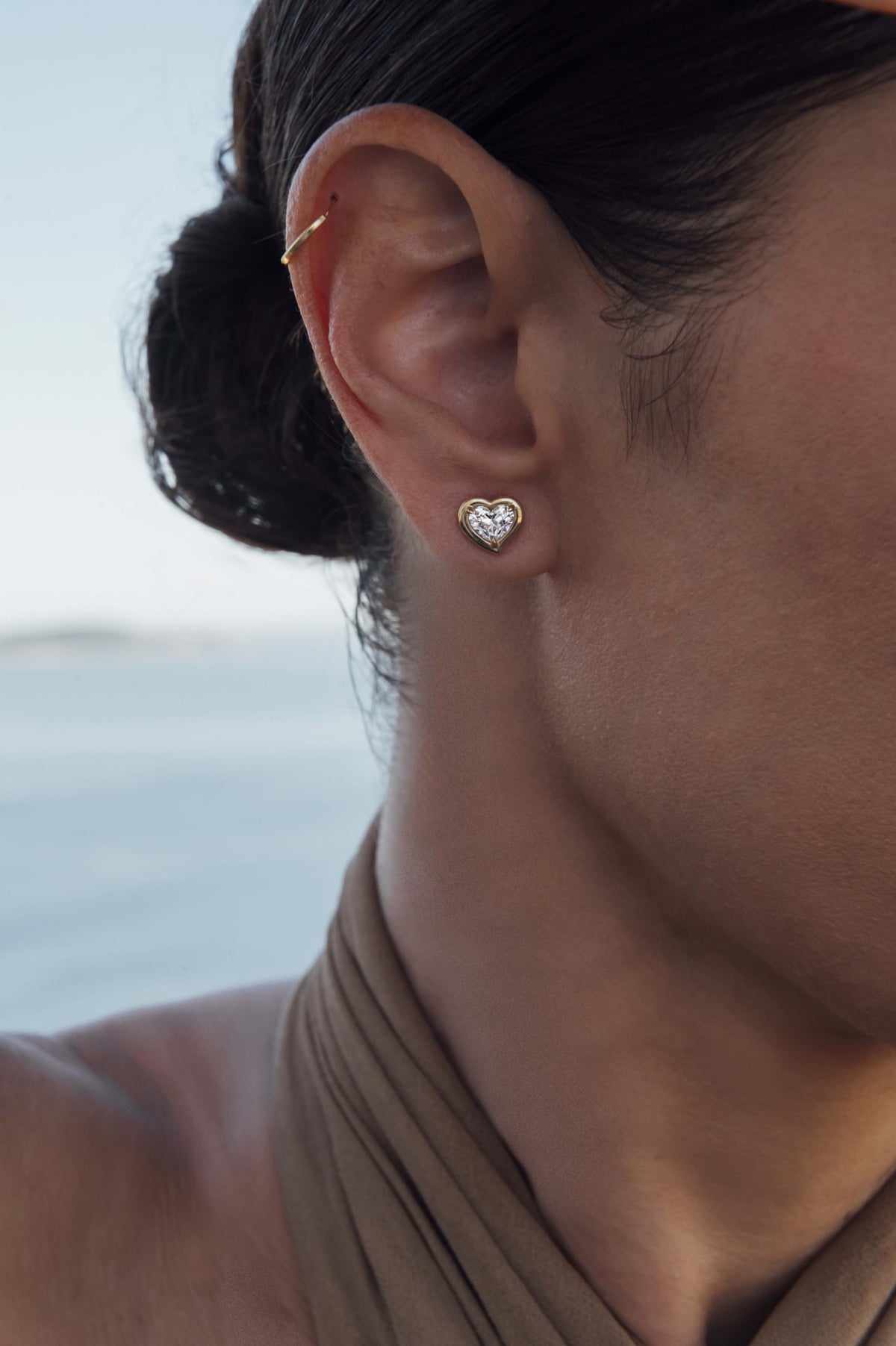 Heart shape diamond stud earrings in 18k yellow gold, worn on the ear