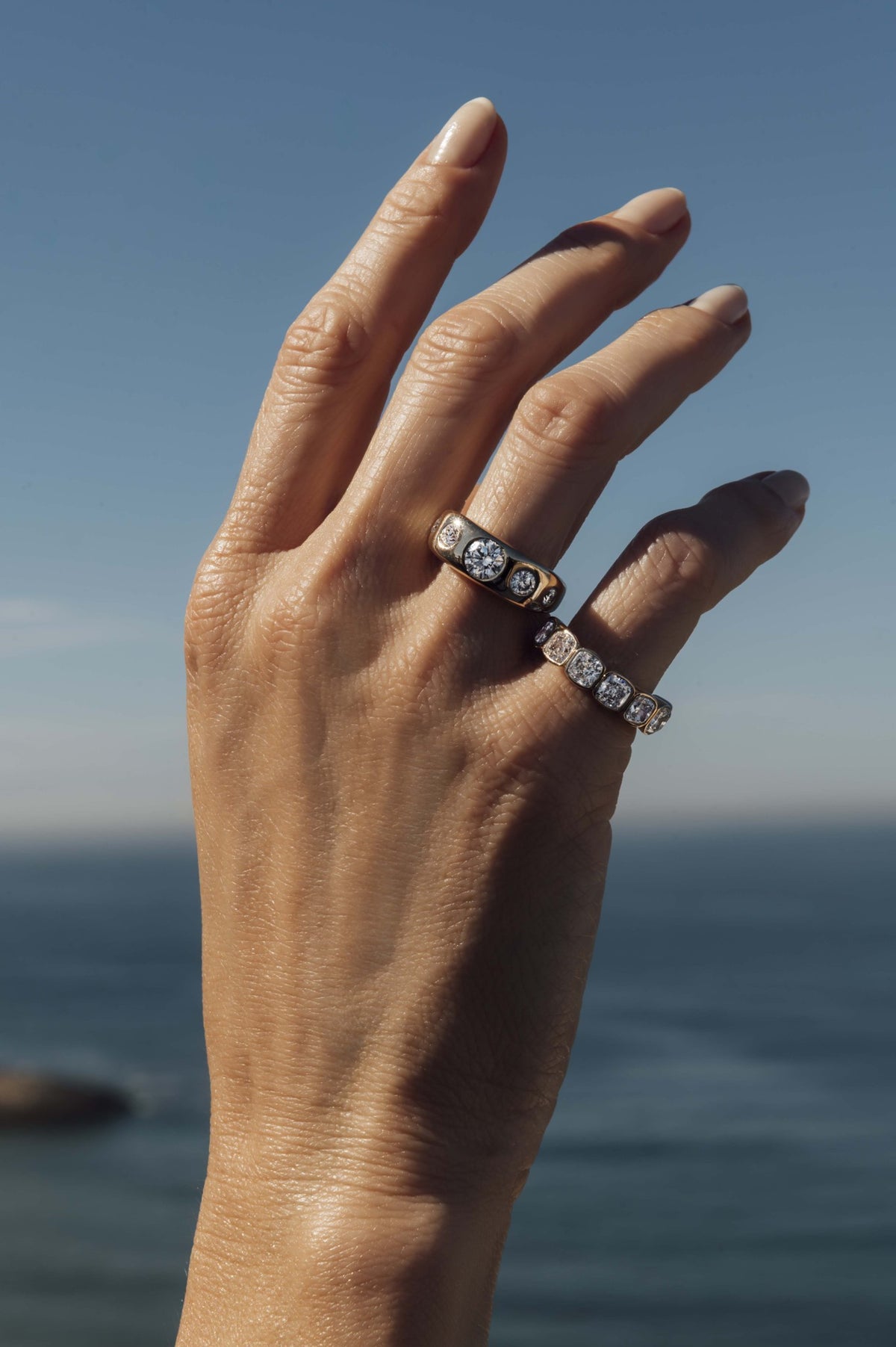 Cushion cut diamond bezel set half eternity band in 18k yellow gold, worn on the hand